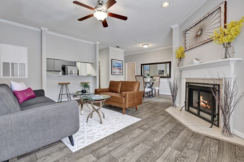 A living room with wood-style flooring, ceiling fan, and fireplace at Village at Caldwell Mill in Birmingham, AL