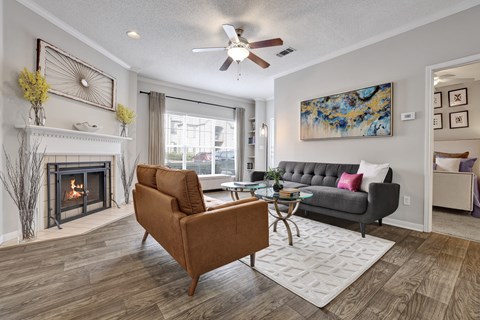 A living room with wood-style flooring, ceiling fan, and fireplace at Village at Caldwell Mill in Birmingham, AL