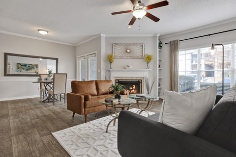 Living room and dining room with ceiling fan plank flooring and fireplace at Village at Caldwell Mill in Birmingham, AL