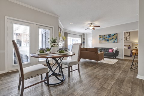 A dining room and living room with wood-plank flooring and ceiling fan at Village at Caldwell Mill Apartments in Birmingham, AL