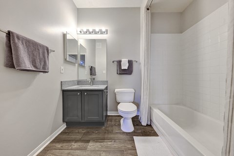 bathroom with wood-style flooring and white bathtub/shower combo at Village at Caldwell apartments in Birmingham, AL