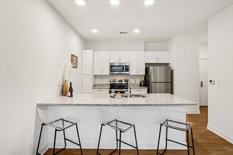 A kitchen with white cabinets and a marble countertop.