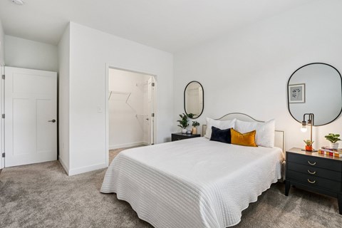 A bedroom with a large bed, a dresser, and a mirror.