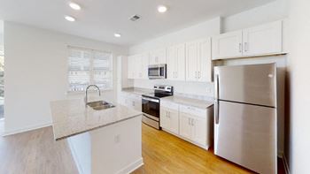 A kitchen with white cabinets and a stainless steel refrigerator at Wesley Place Apartments in Indianapolis, Indiana.