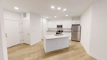 Open floor plan with large kitchen island and wood plank flooring at Wesley Place Apartments in Indianapolis, Indiana