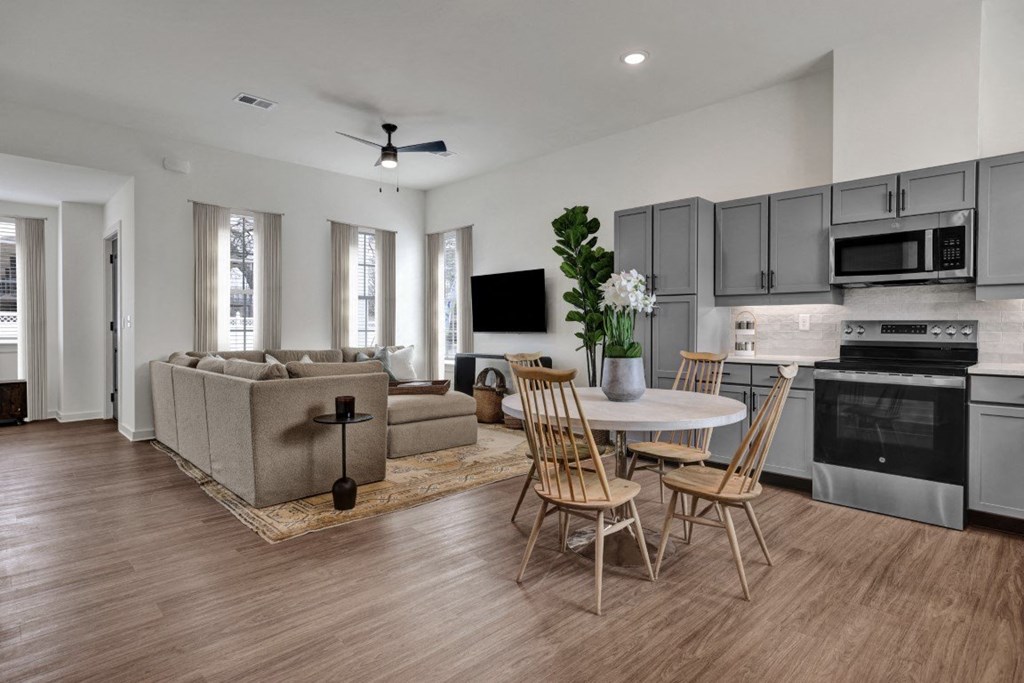 A modern kitchen and living room with wood-designed flooring at West Row Townhomes and at West Row Townhomes at West Row Lofts and Townhomes in Birmingham, AL