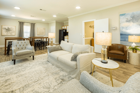 A well-lit living room with a grey sofa and a wooden floor.