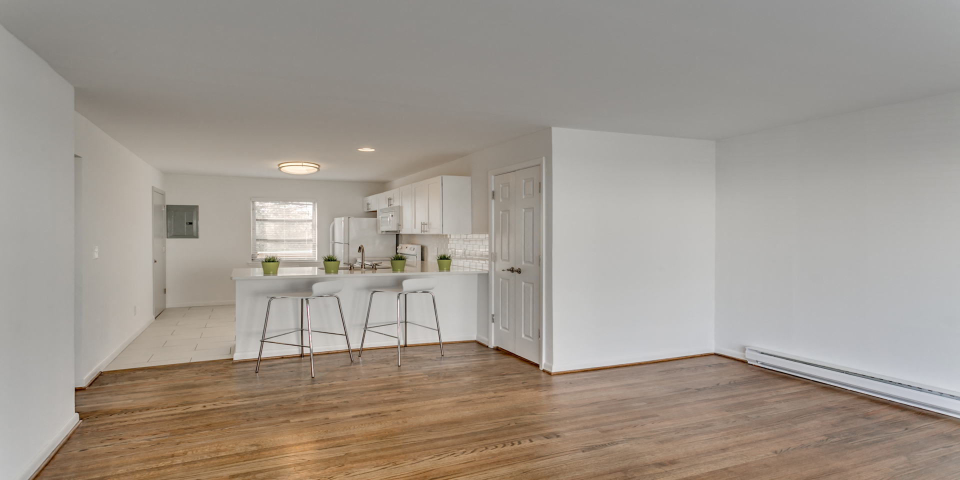 a kitchen with white cabinets and a bar with three stools