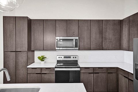 A modern kitchen with dark wood cabinets and white countertops.