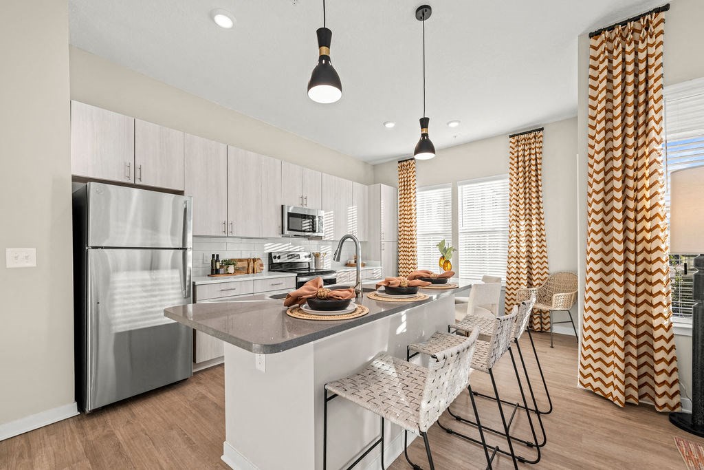 a kitchen with a large island and a stainless steel refrigerator