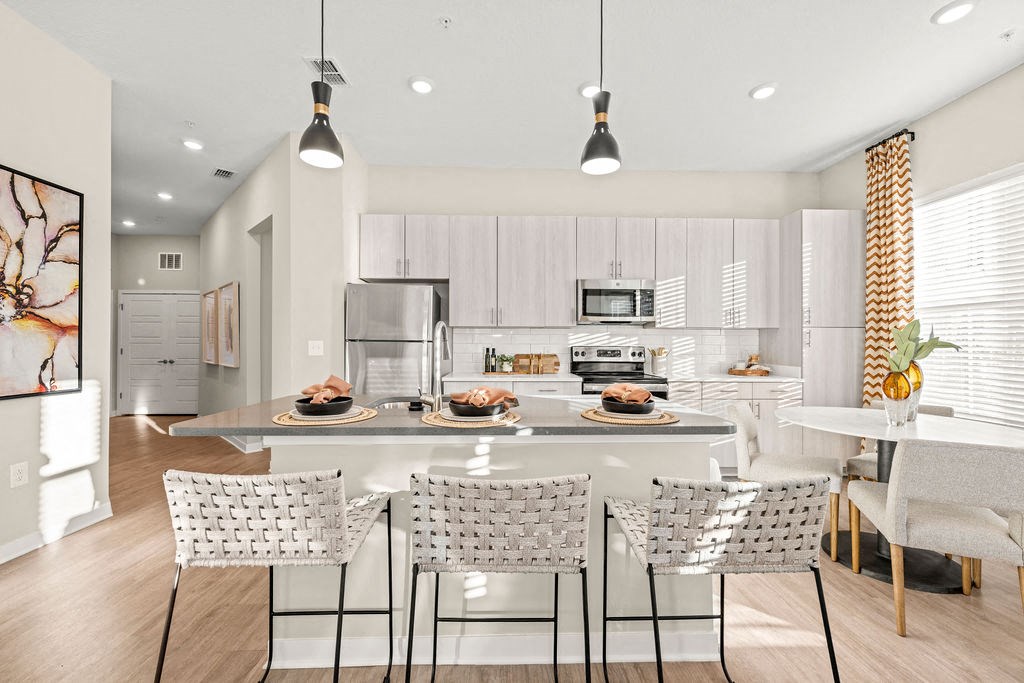 an open kitchen and dining room with white cabinets and a marble counter top