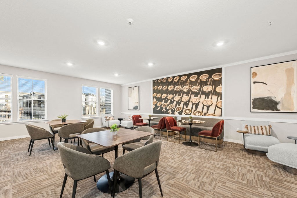 a living room with tables and chairs and a wall of paintings