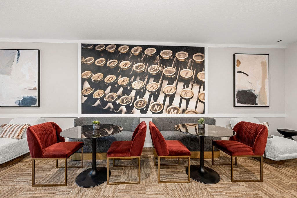 a living room with two tables and chairs and a large painting on the wall