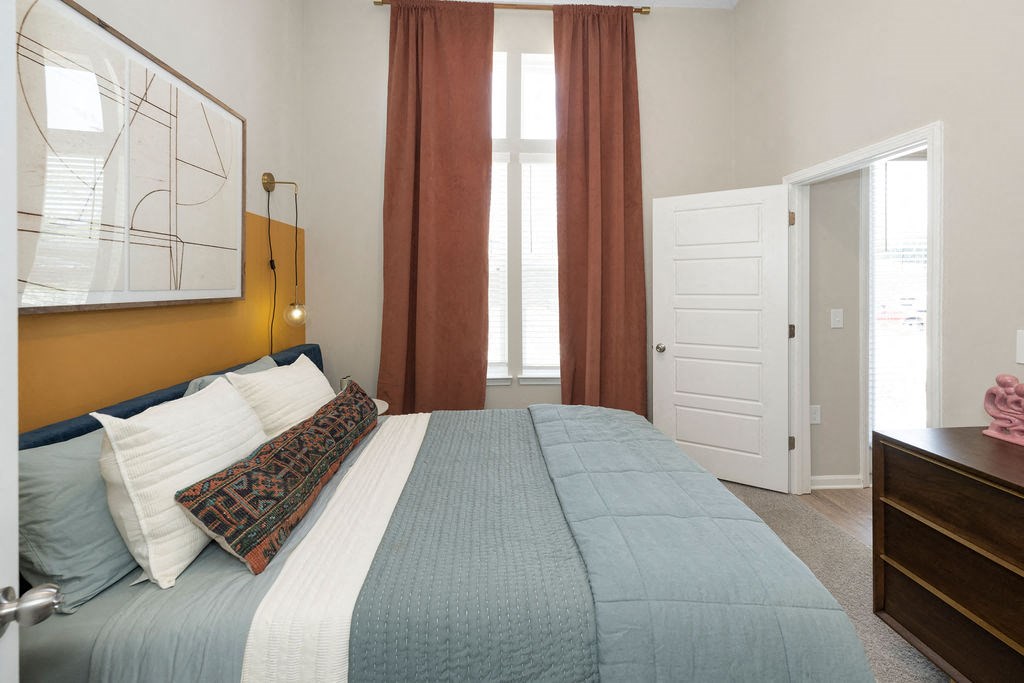 a bedroom with a bed and two windows      and a door