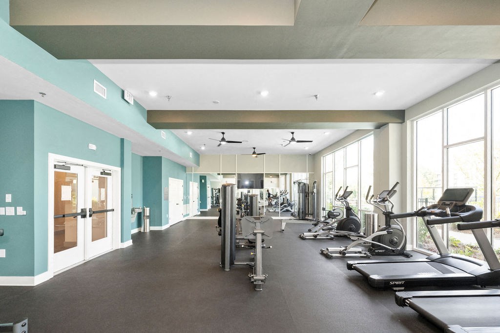a gym with cardio equipment and windows in a building
