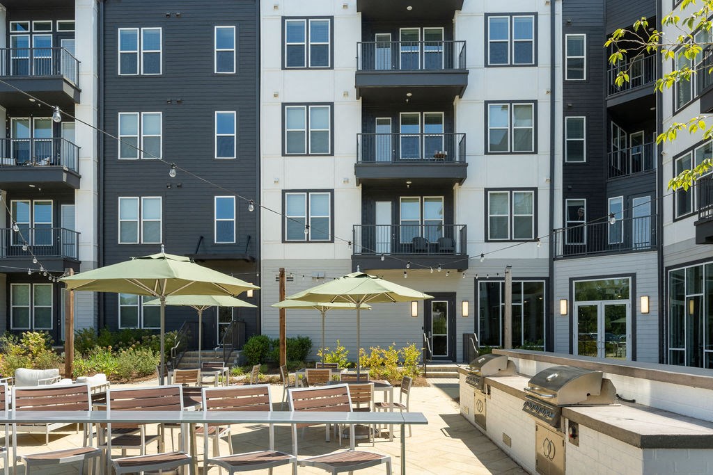 a patio with tables and umbrellas in front of an apartment building