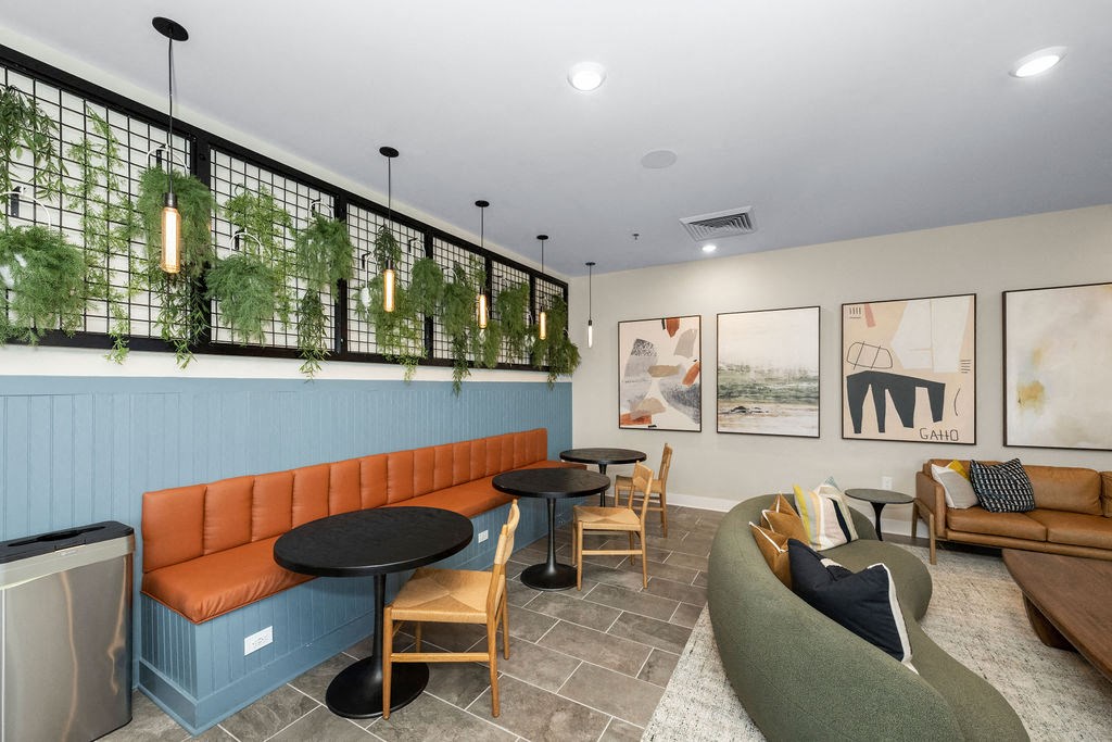 a lobby with couches tables and chairs and a wall with plants