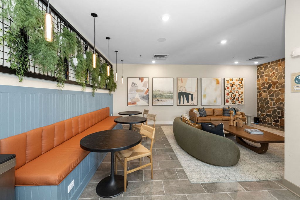 a lobby with couches and tables and a wall of plants