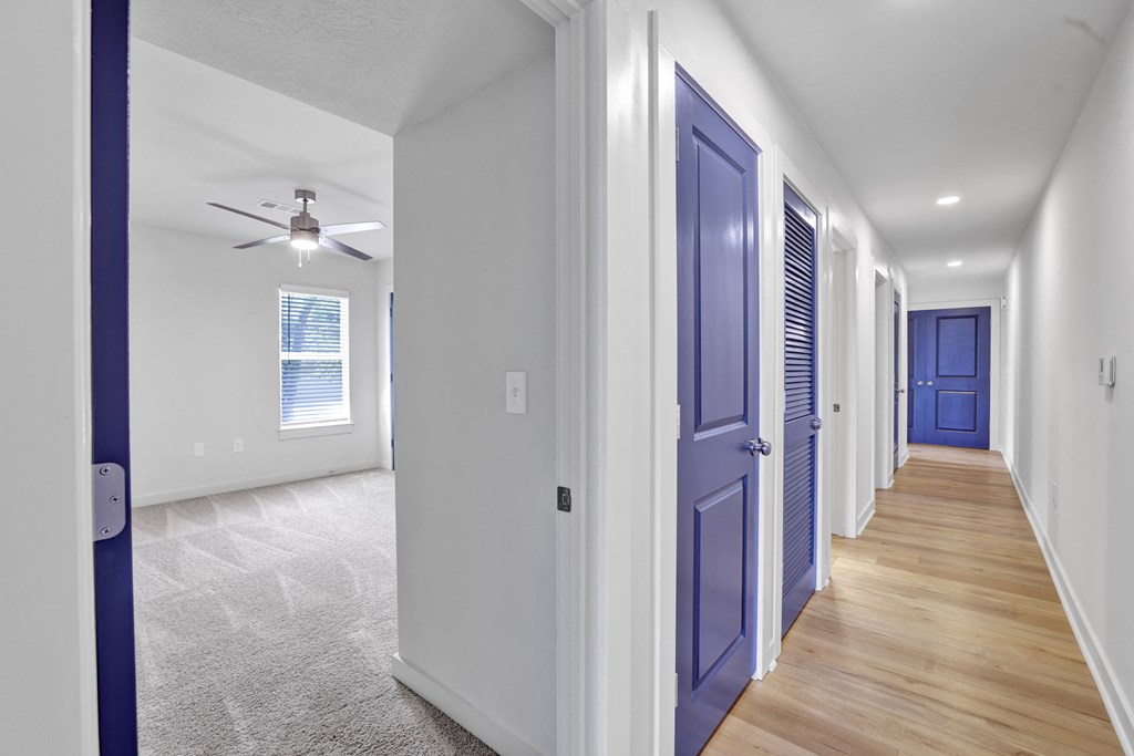 a hallway with blue doors and a ceiling fan