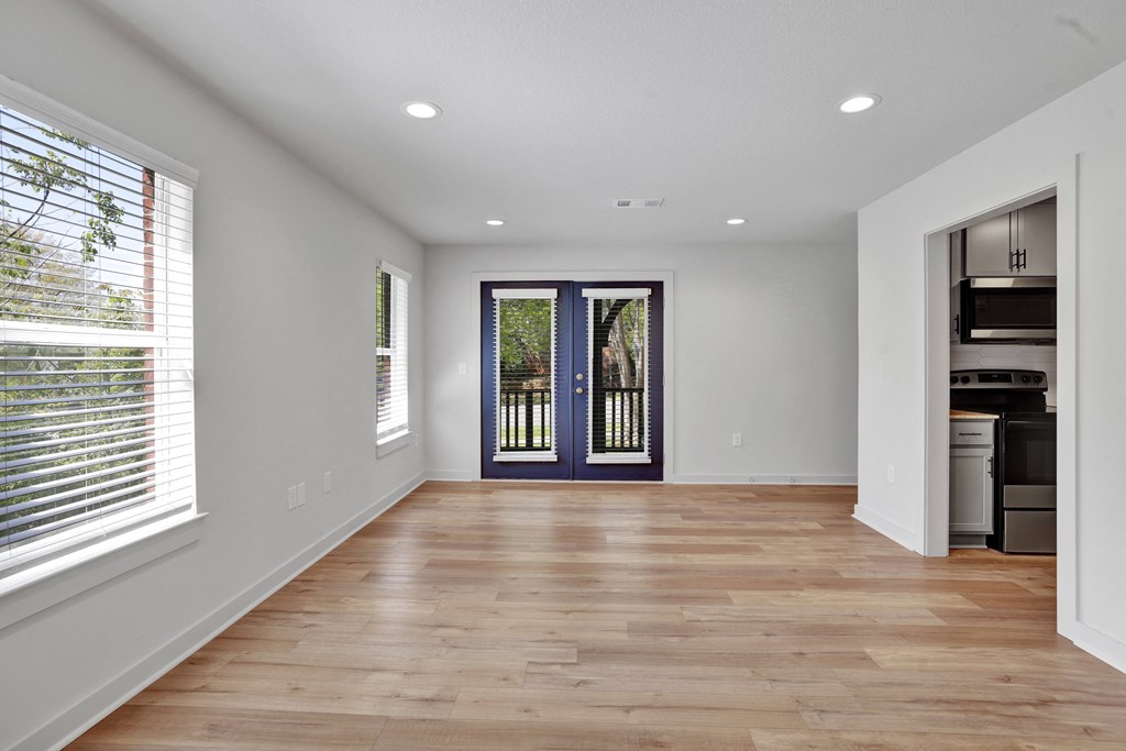 a living room with a hardwood floor and a door to a kitchen