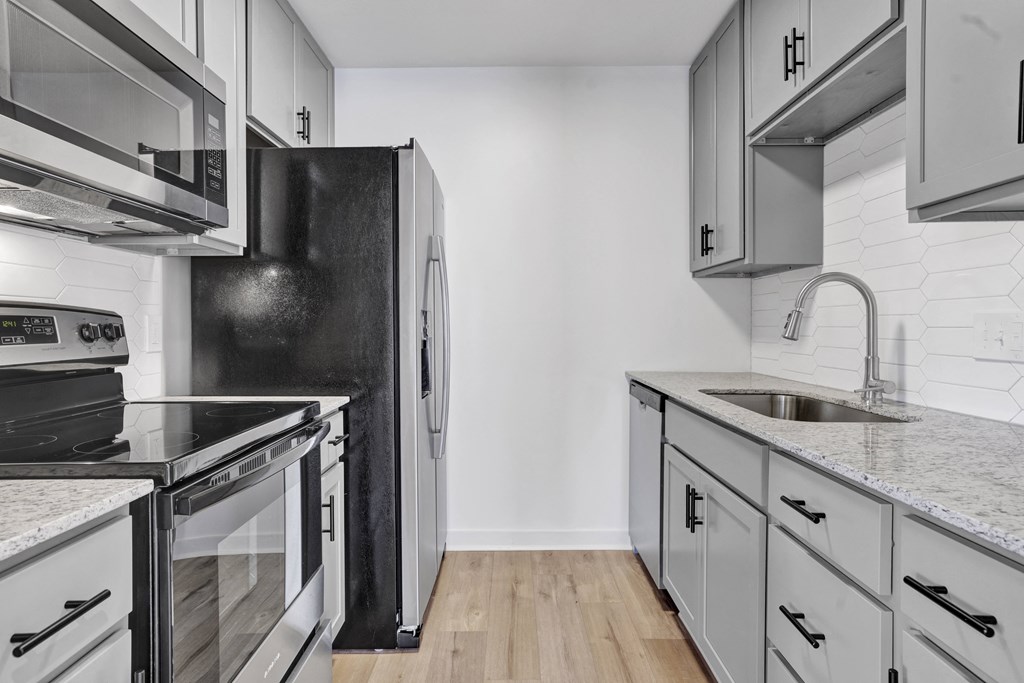 an empty kitchen with white cabinets and stainless steel appliances