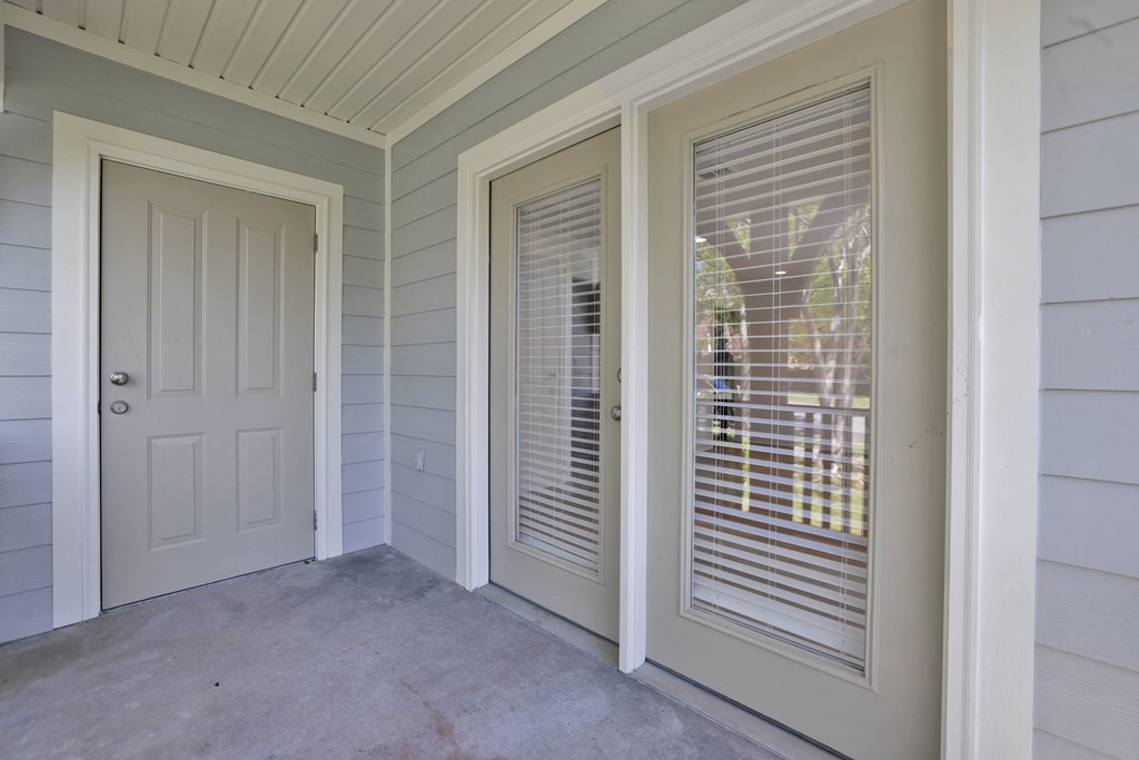 the front porch of a home with two windows and a white door