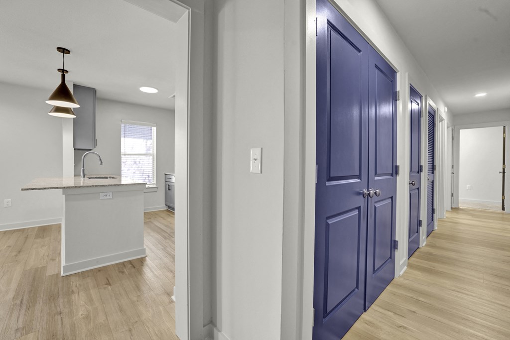 a hallway with blue doors leading to a kitchen and a counter top in a house