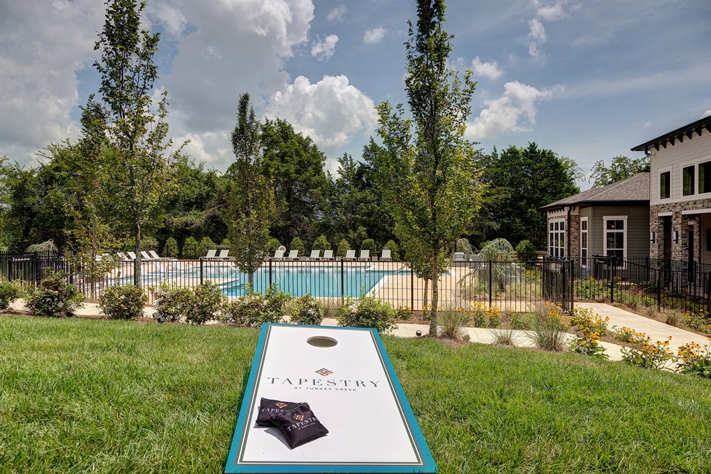 a backyard with a pool and a game board in the grass