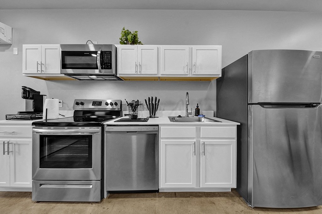 Pet-Friendly Apartments In Downtown Birmingham, AL - Market Lofts On Third - Kitchen With Stainless Appliances, White Cabinetry, And Quartz Countertops