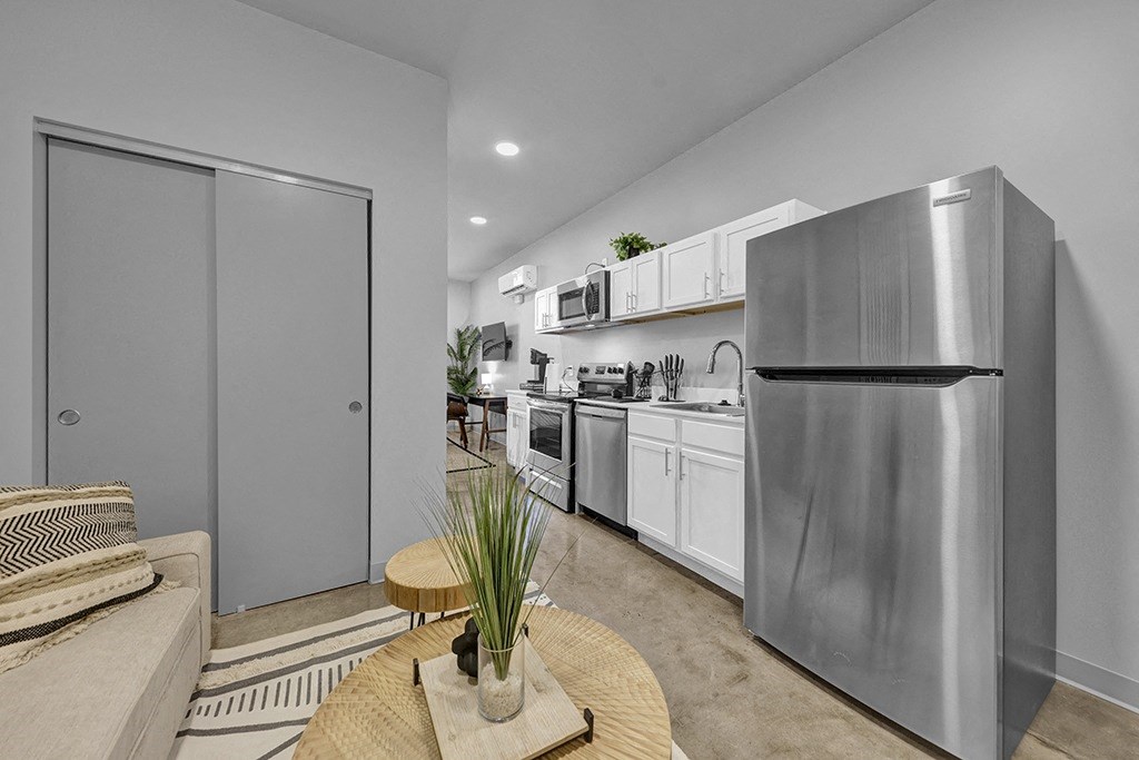 an open kitchen and living room with a stainless steel refrigerator