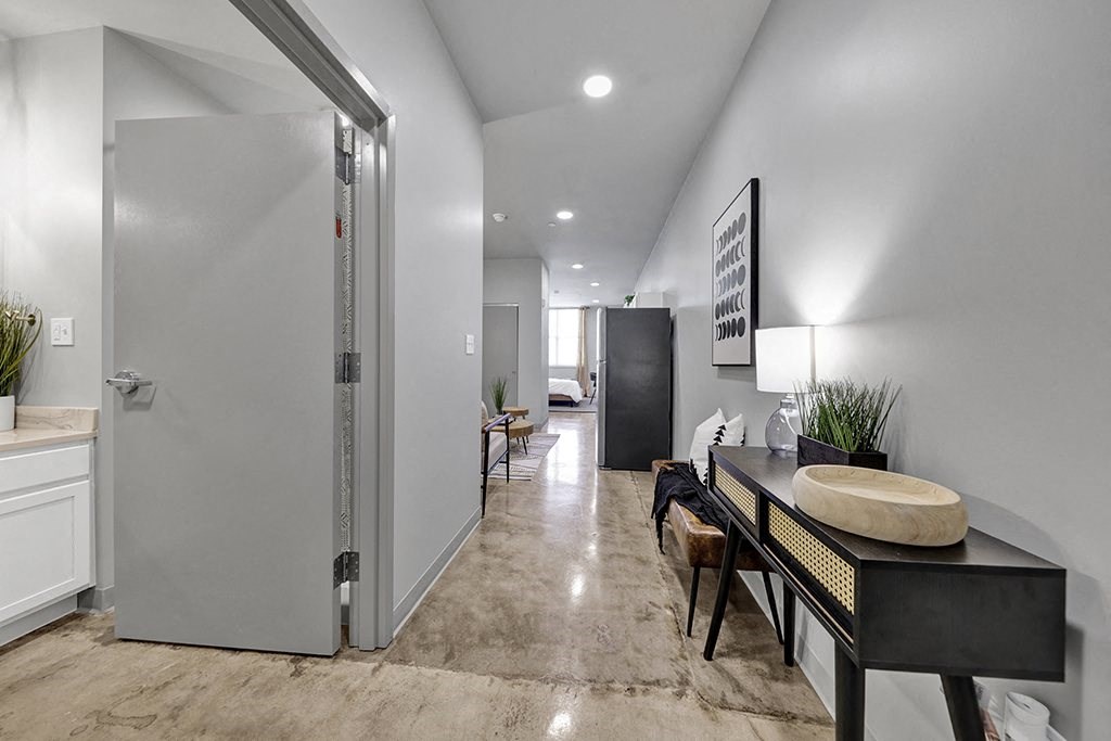 a long hallway with a desk and a door to a living room