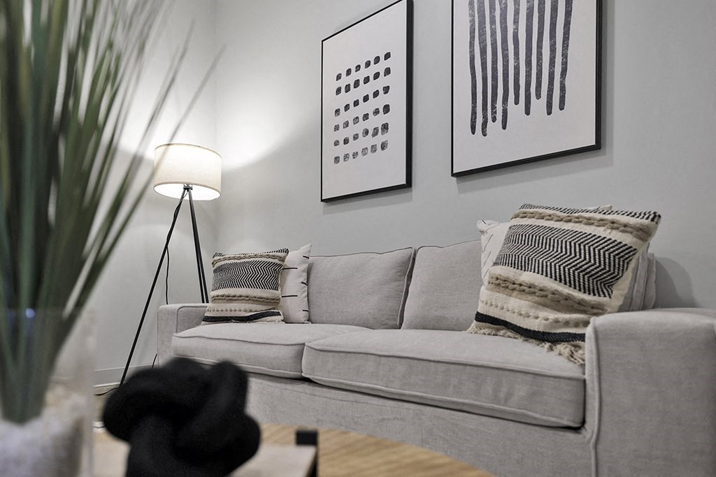 a living room with a couch and pillows and a lamp