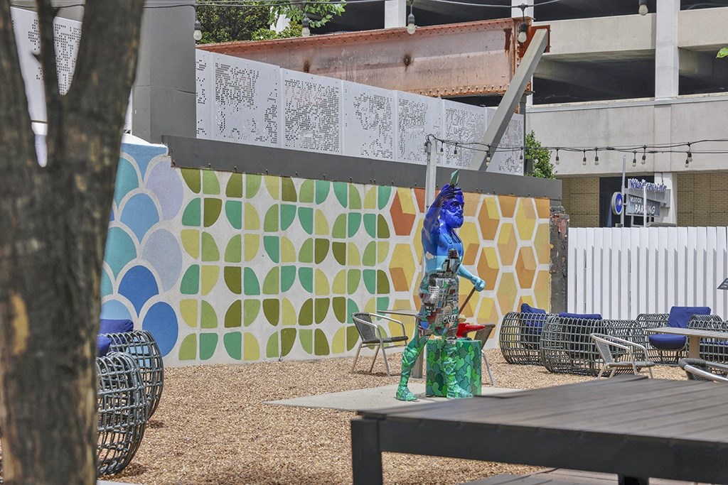 a statue of a blue cat on a tree in a courtyard