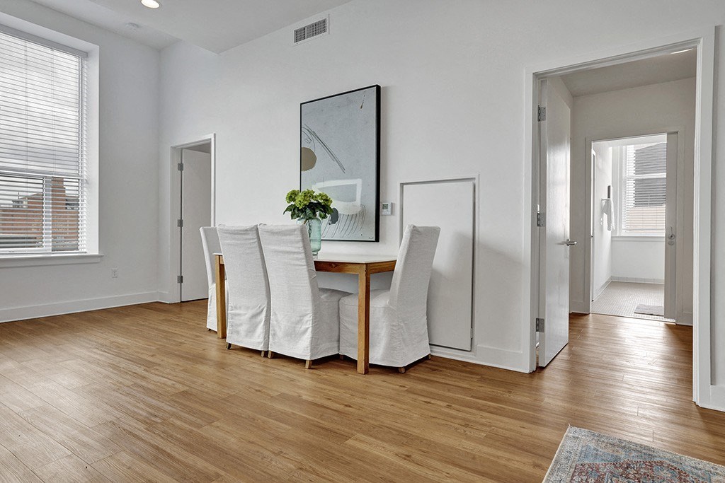 a dining room with white chairs and a table with a mirror on the wall