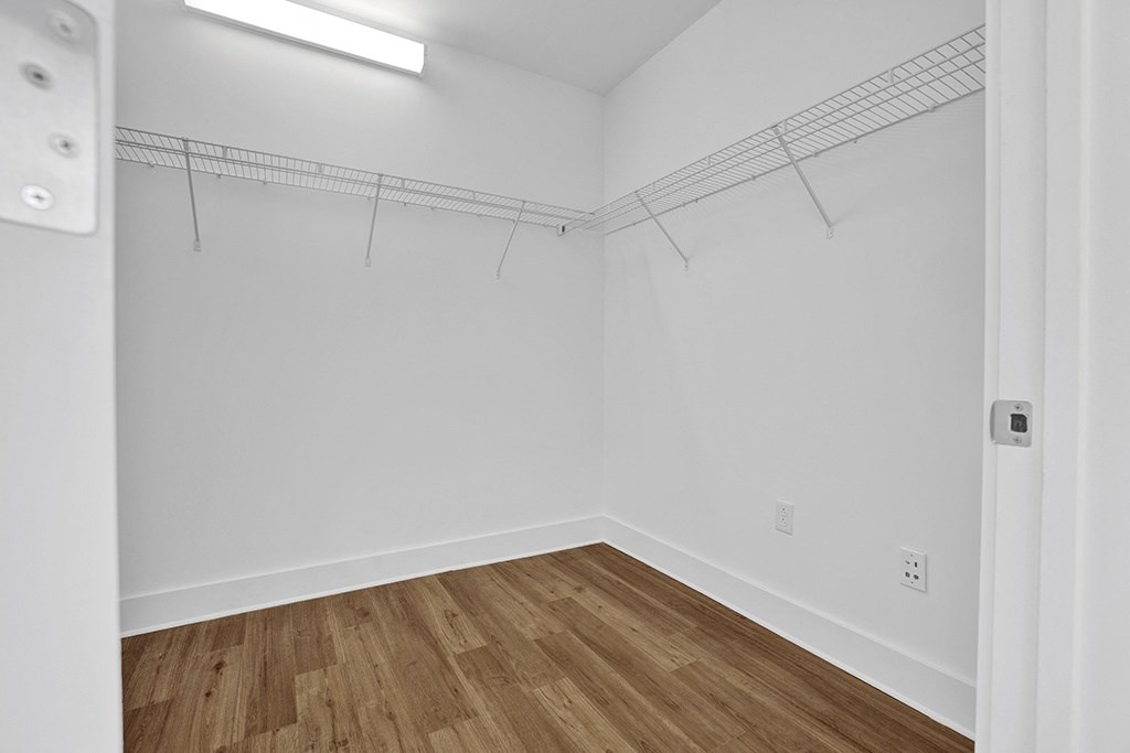 a large closet with white walls and a wooden floor