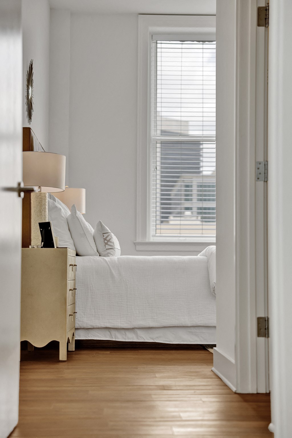 a bedroom with a bed and a window and a wooden floor