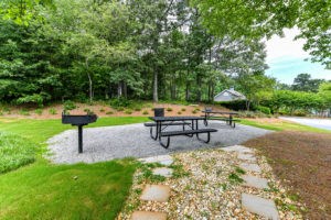 two picnic tables in a park with a fire pit