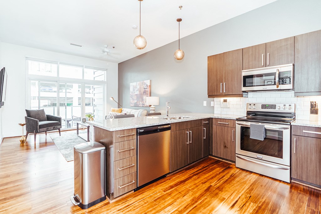 a large kitchen with wooden floors and stainless steel appliances at 20 Midtown, Birmingham, 35233