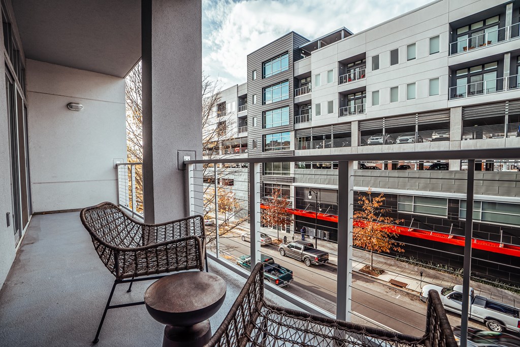 a balcony with a chair and a table overlooking a city street at 20 Midtown, Birmingham, 35233
