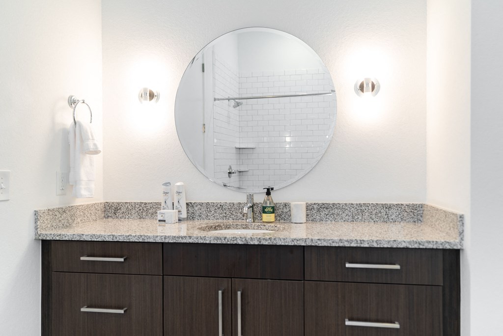 a bathroom with a vanity and a round mirror on the wall at 20 Midtown, Birmingham, 35233