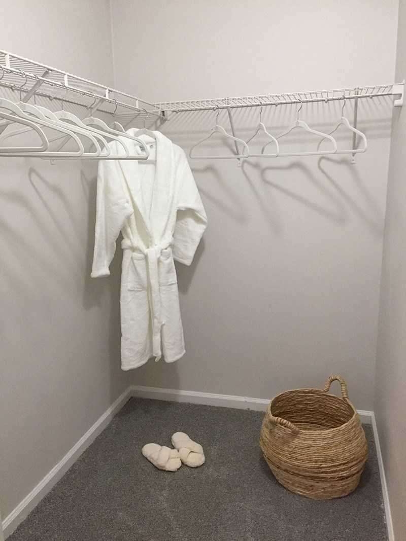 a walk in closet with a white robe and white shoes