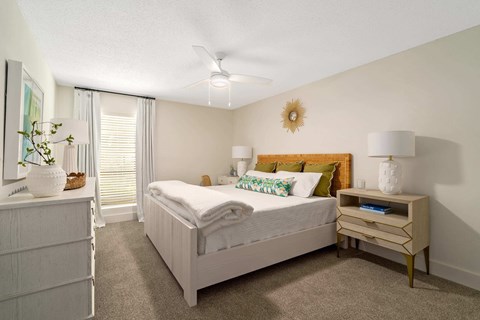 A bedroom with a bed, nightstand, and a plant on the side table.