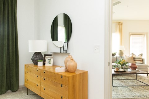 a living room with a dresser and a mirror on the wall