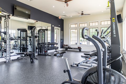 a gym with cardio equipment and weights on the floor
