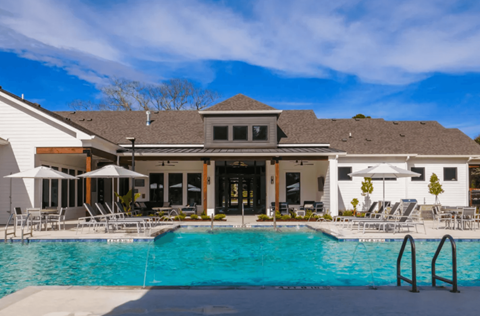 A large swimming pool in front of a house with a white exterior.