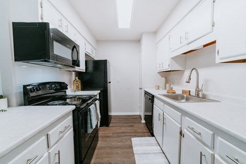 a kitchen with white cabinets and black appliances and a sink