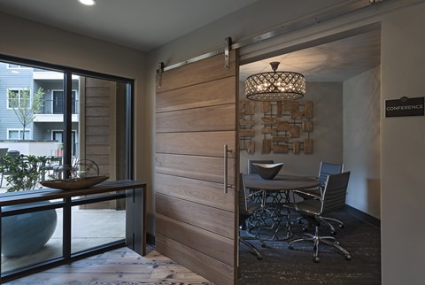 A conference room with a wooden door and a glass table with chairs.
