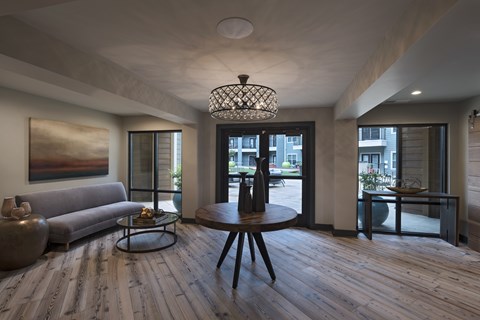 A modern living room with a grey couch, a wooden coffee table, and a large painting on the wall.