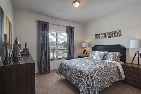 A bedroom with a large bed and a nightstand with a lamp.
