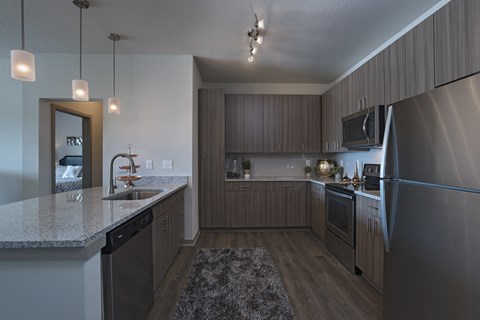 A modern kitchen with a granite countertop and stainless steel appliances.